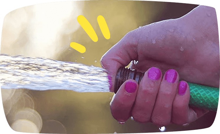 vrouwenhand houdt een tuinslang vast voor het limbodansen met water.